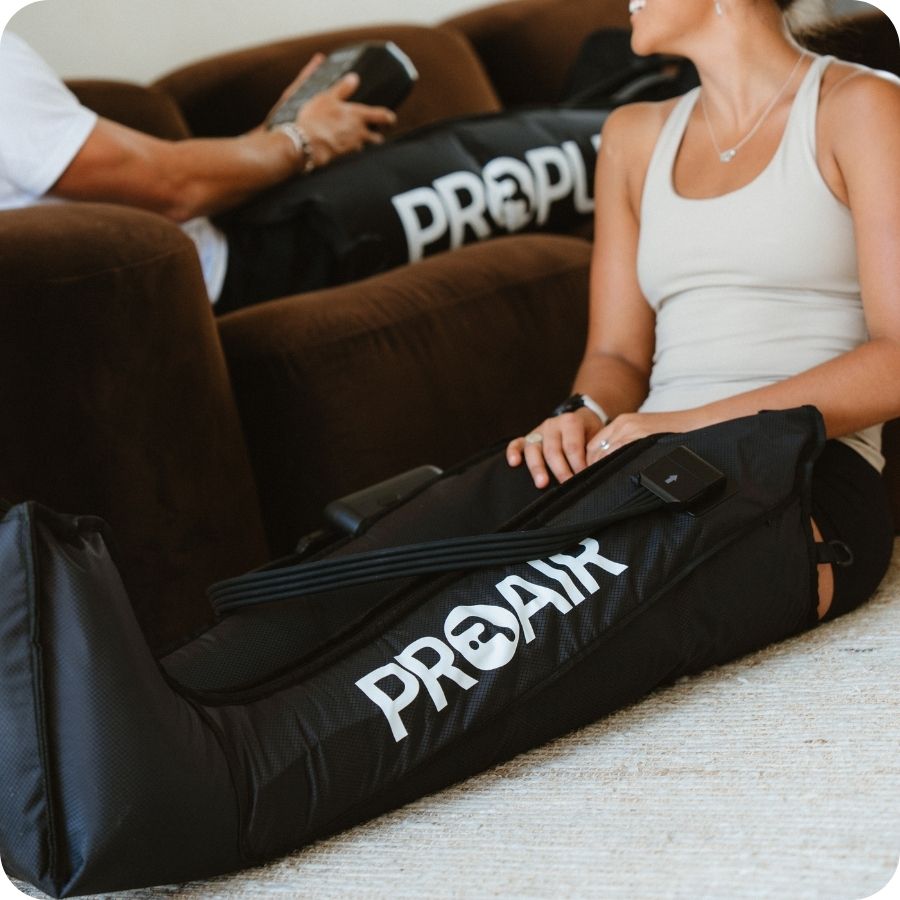 Two people using PROAir compression boots on the couch