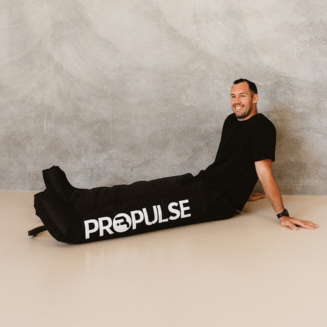 Man sitting in a studio wearing PROPulse compression leg attachments