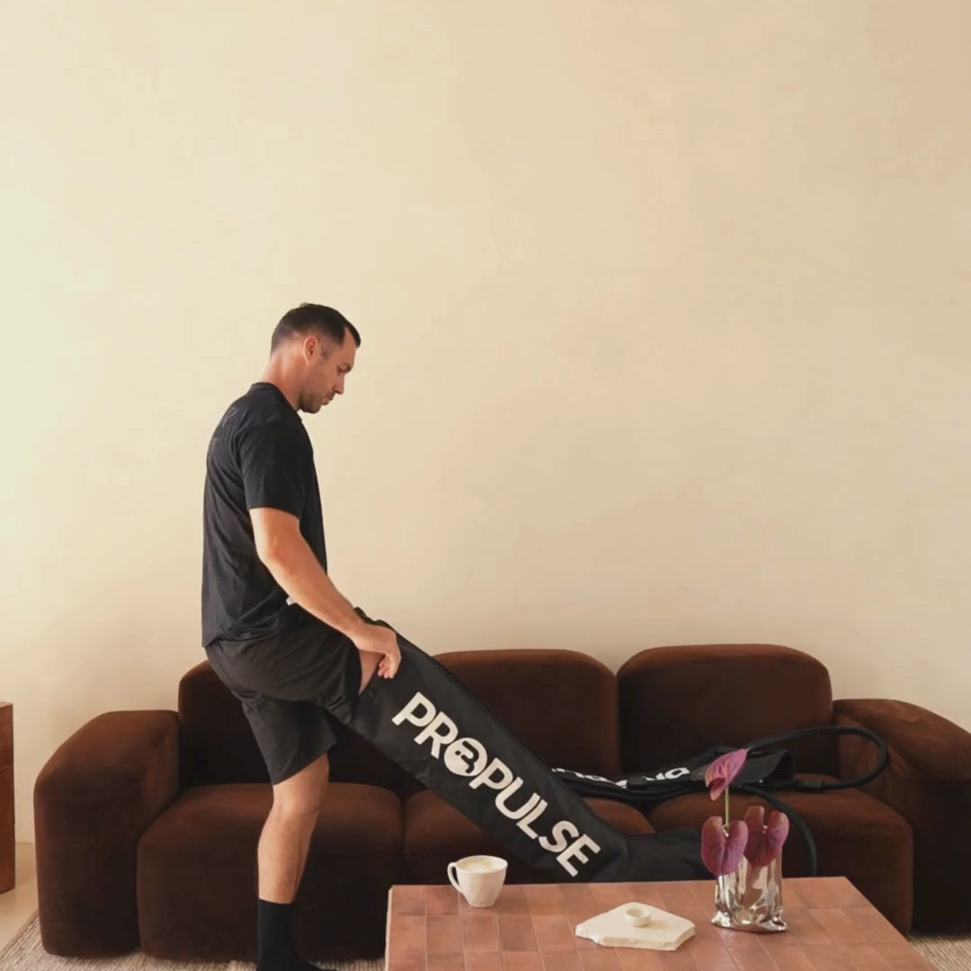 Man using PROPulse compression boots at home on the couch